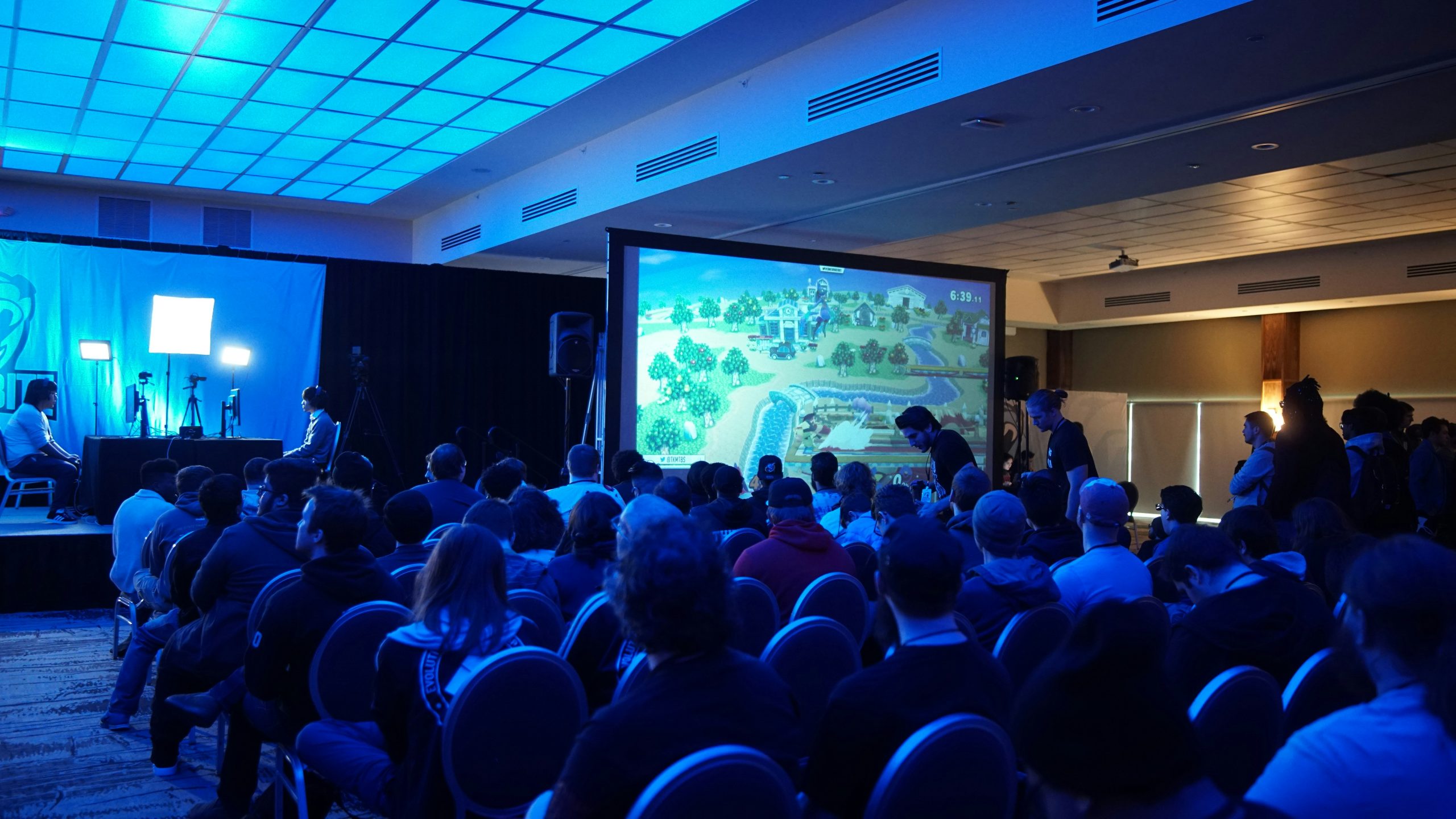 Sala de conferencias con estructuras prefabricadas llenas de asistentes a un evento corporativo.